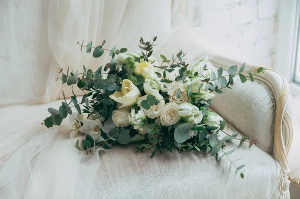 Belo buquê de casamento de rosas brancas e orquídeas em um velho sofá branco clássico . — Fotografia de Stock