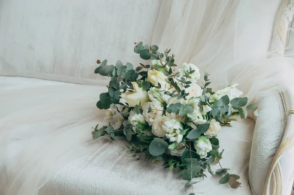 Belo buquê de casamento de rosas brancas e orquídeas em um velho sofá branco clássico . — Fotografia de Stock