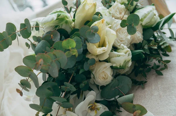 Belo buquê de casamento de rosas brancas e orquídeas em um velho sofá branco clássico . — Fotografia de Stock