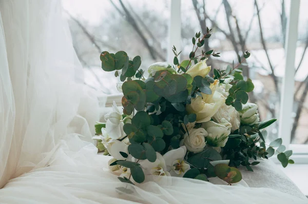 Belo buquê de casamento de rosas brancas e orquídeas em um velho sofá branco clássico . — Fotografia de Stock