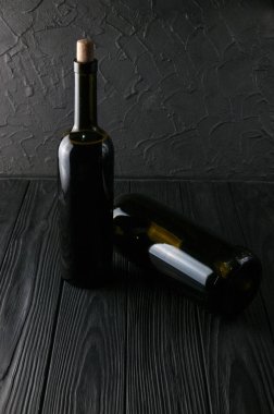 Şişe şarap üzüm ve peynir Camemberg siyah bir ahşap zemin üzerine.