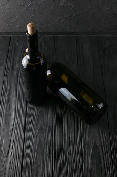 Bottles of wine on a black wooden background with grapes and cheese Camemberg. — Stock Photo, Image
