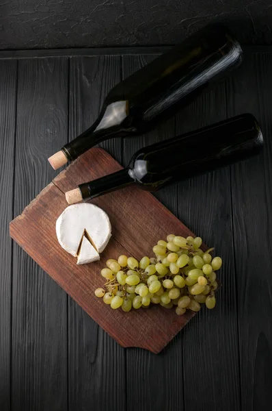 Garrafas Vinho Sobre Fundo Madeira Preta Com Uvas Queijo Camemberg — Fotografia de Stock