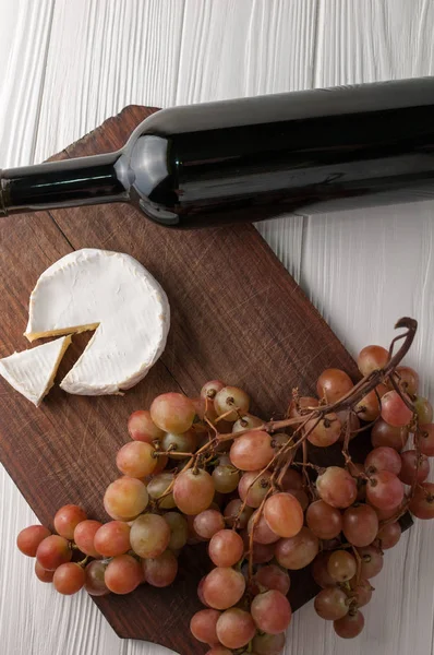 Weinflaschen Auf Weißem Holzgrund Mit Trauben Und Camembert — Stockfoto