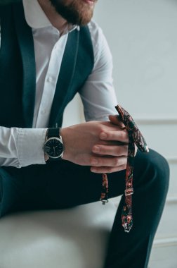 Patronun kırpılmış görüntüsü, el ele tutuşması, kelebeği elinde tutması, pahalı ve şık bir saat, ön manzara. Kavram