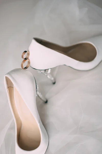 Bílé svatební boty s kroužky na stoličce. — Stock fotografie