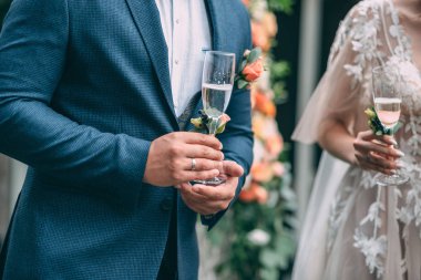 Gelin ve damat düğün gözlük tutun ve düğün kemer, kum töreni arka plan üzerinde durmak.
