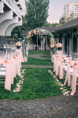 Güzel bir düğün hazırlığı. Düğün merasiminin alanı. Yuvarlak kemer, çiçeklerle süslenmiş beyaz sandalyeler, yeşillik. Sevimli, modaya uygun kırsal dekor. Festival dekorunun bir parçası, çiçek aranjmanı..