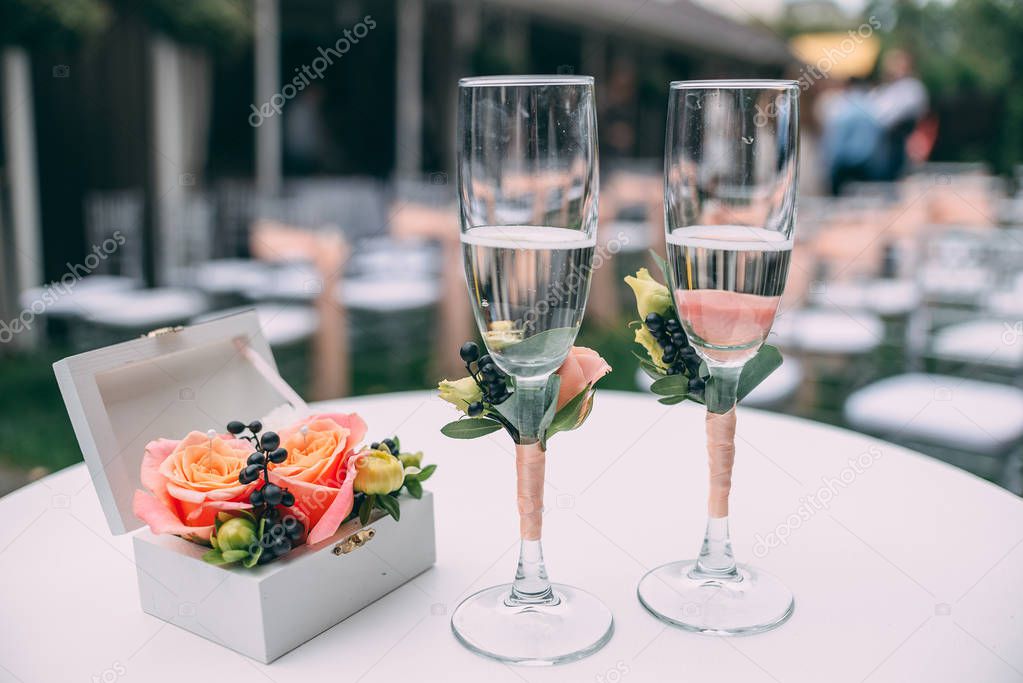 Two wedding glasses and bridal bouquet on stone in summer garden