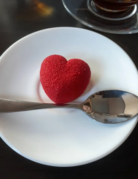 Como un pastel de corazón yace en un plato blanco sobre una superficie de madera — Foto de Stock