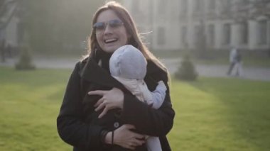 Genç, güzel bir anne bebek taşıyıcı eski bir kale önünde oturan küçük bir çocuk dans