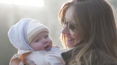 Genç güzel anne küçük bebeği öpüşme, gülüyor, atlama