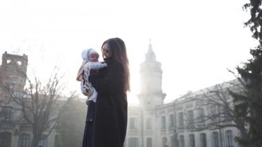 Genel bir plan ben atlama ve eski bir kale önünde bir bebek askı yaşındaki kızıyla birlikte döne döne genç bir kadın Full Hd bir aile gülüyor