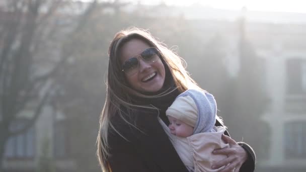 Een jonge mooie moeder wervelende met haar jaarling dochter in een draagdoek baby voor een oud kasteel — Stockvideo
