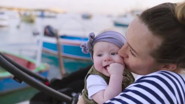 Um plano de close-up de uma mãe beijando seu bebê ano perto do mar — Vídeo de Stock