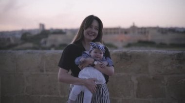 Siyah bir tişört dansları genç bir kadın ile deniz kıyısına yakın çizgili takım elbiseli kızı