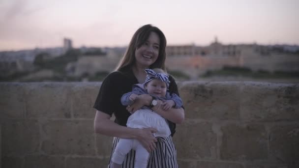 Een jonge vrouw in een zwart T-shirt-dansen met haar dochter in een gestreepte pak in de buurt van de zeekust — Stockvideo