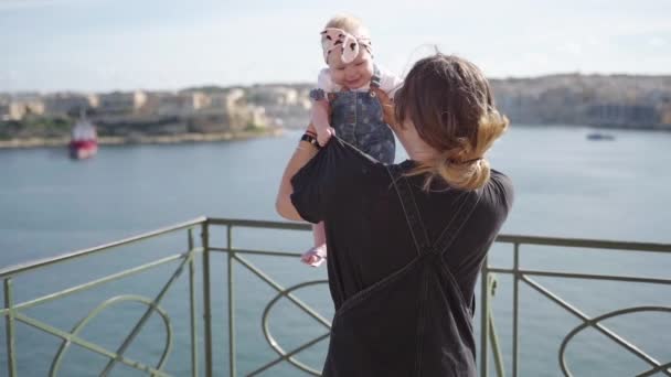 Een lachende baby in slowmo met moeder in de buurt van de zee — Stockvideo