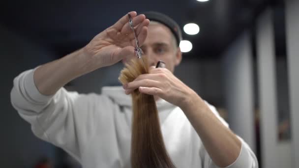 Un peluquero macho moliendo un mechón de pelo castaño y peinándolo — Vídeos de Stock