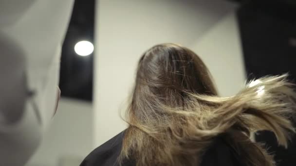 Un peluquero está secando un cabello castaño desbordante — Vídeos de Stock