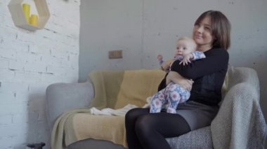 Genç bir anne bir kanepe oturma odasında bebeği ile çalış
