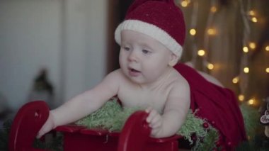 Noel Baba kızağa bir Noel şapka ve takım elbise, yılbaşı photoshoot yatan küçük bir bebek