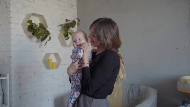 A young mother whirls with her baby in the living room — Stock Video
