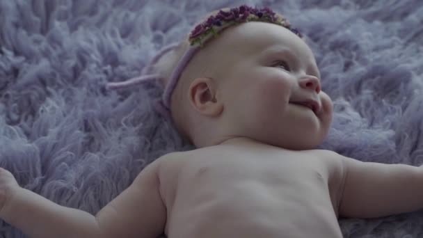 Een fotosessie van een naakte kleine baby liggend op de paarse cover en lachen in slow motion — Stockvideo