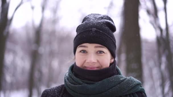 Mladá dívka stojí mezi zasněženými stromy v zimě lesní a směje se — Stock video