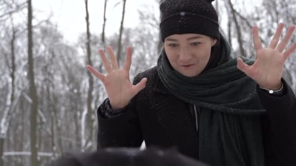 Een jonge vrouw maakt gezichten voor haar pasgeboren baby in een kinderwagen in de winter — Stockvideo