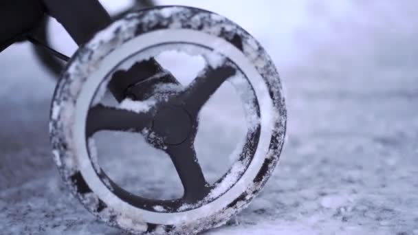 눈 덮인 아스팔트에 아기 유모차 바퀴의 클로 우즈 업 계획 — 비디오