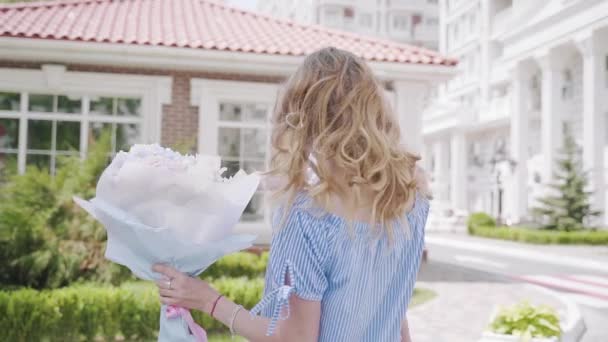Мати кружляє біля будинку з маленькою донькою і букетом — стокове відео