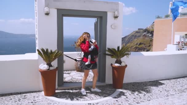 Девушка стоит у красивой двери на острове Санторини, попадая в камеру на девушку и вид на море — стоковое видео