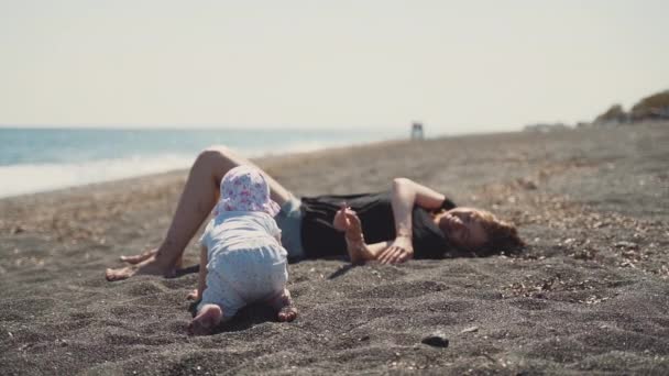 En mor och en liten dotter på den vulkaniska sanden — Stockvideo