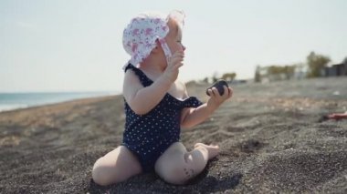 Küçük bir kız siyah volkanik kum sahilde bir taş ile oynar