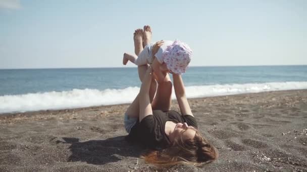 A mother and a little daughter play on the sea coast — Stock Video