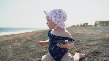 Deniz kıyısında bir taşla oynayan küçük kızın yakın çekim planı