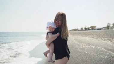 Bir anne ve kızı deniz kıyısında durmak ve dalgalar üzerinde izlemek