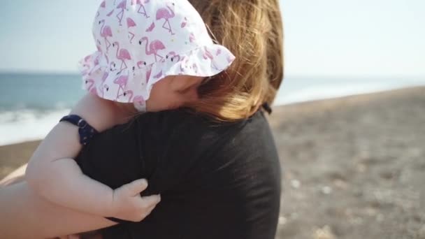 En längtan bebis kramar sin mamma på stranden — Stockvideo