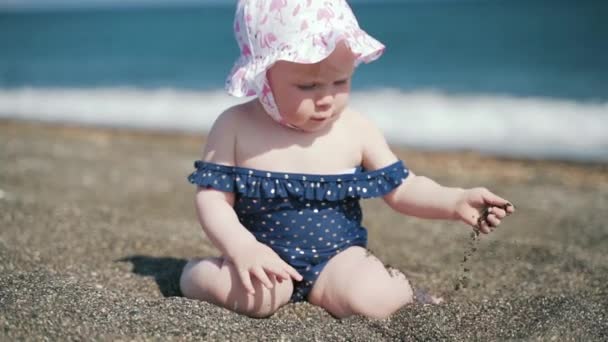 一个严肃的一岁女孩在海边玩鹅卵石的特写计划 — 图库视频影像