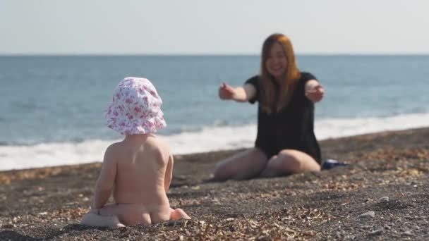 Una madre llama a su pequeña hija desnuda en la playa de arena volcánica — Vídeos de Stock