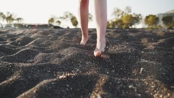 Egy közeli terv egy nő lábak séta a fekete homokos strand — Stock videók