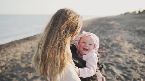 Un primer plano de un bebé sonriente en las manos de la madre en la playa — Vídeo de stock