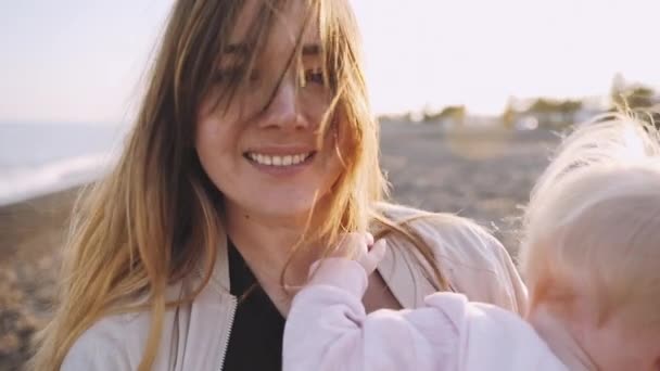 Un piano di primo piano di una donna che gira con il suo bambino sulla spiaggia sull'isola di Santorini a slowmo — Video Stock