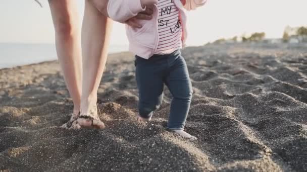 Ein Gesamtplan eines kleinen Mädchens, das versucht, seine ersten Schritte am Meer zu machen — Stockvideo