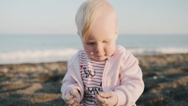 En längtan flicka leker med småsten på stranden — Stockvideo