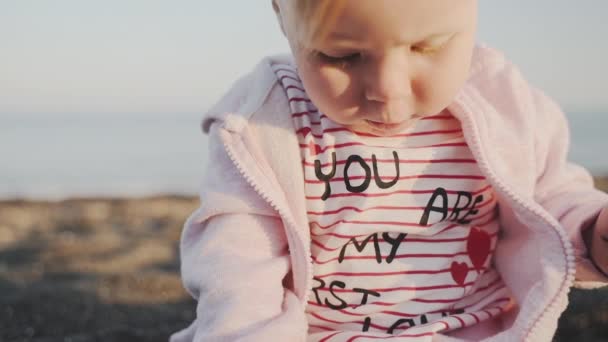 Un piano di primo piano di una bambina seria seduta vicino al mare — Video Stock