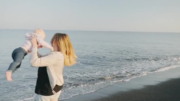 Una mujer gira con su bebé en la playa de la isla de Santorini en slow mo — Vídeo de stock