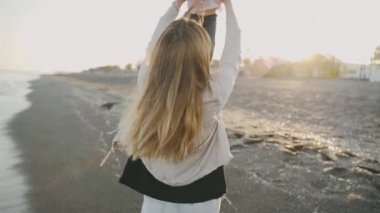 Bir kadın slowmo Santorini Adası'nda sahilde bebeğini atar