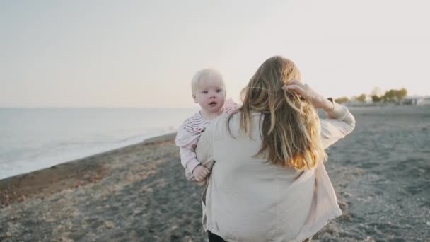 En ung kvinna går längs havskusten med sin längtande dotter — Stockvideo